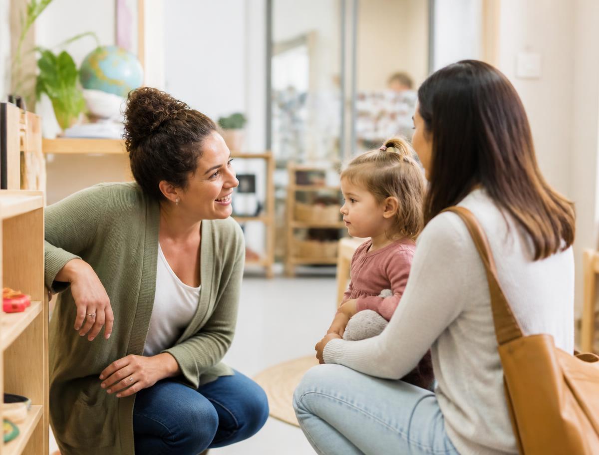 An early childhood educator greeting a parent and toddler at a preschool open house
